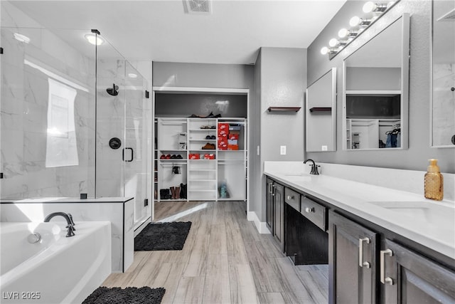 bathroom with vanity, hardwood / wood-style floors, and plus walk in shower