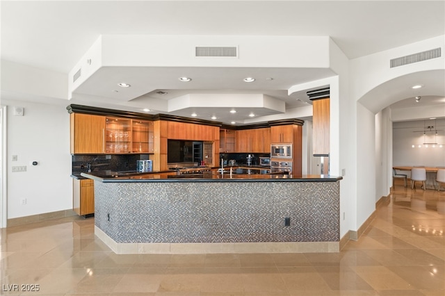 kitchen featuring kitchen peninsula, appliances with stainless steel finishes, light tile patterned flooring, and decorative backsplash