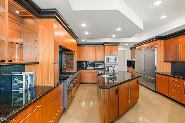 kitchen with light tile patterned flooring, sink, built in appliances, and an island with sink