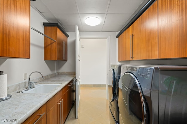 clothes washing area featuring washing machine and dryer, cabinets, and sink