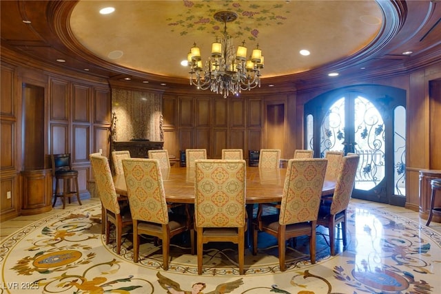 dining space with ornamental molding, a raised ceiling, french doors, and an inviting chandelier