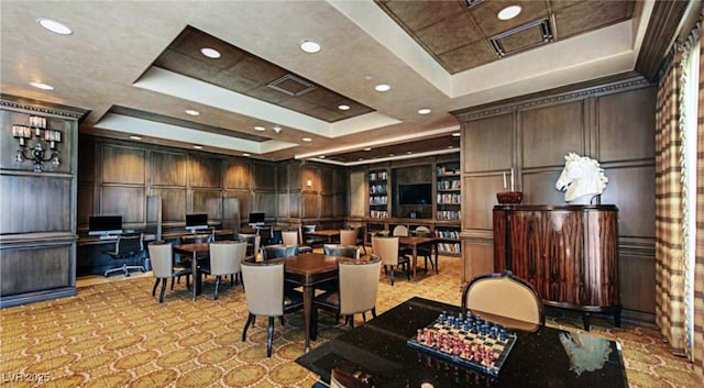 dining area with built in features, light colored carpet, wood walls, and a tray ceiling