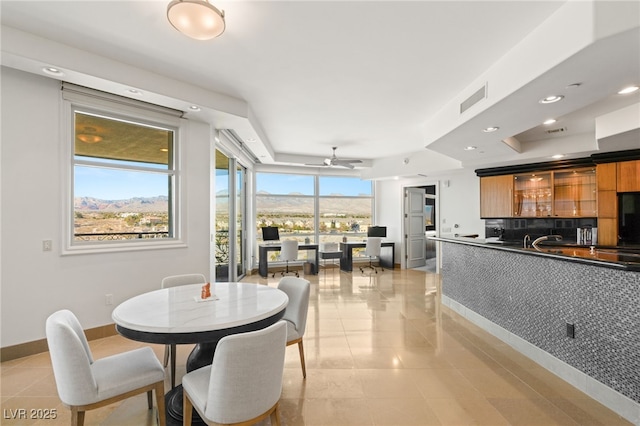 tiled dining area featuring ceiling fan, a mountain view, plenty of natural light, and bar area