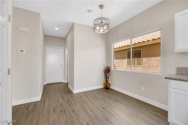 unfurnished dining area with light hardwood / wood-style floors and a chandelier