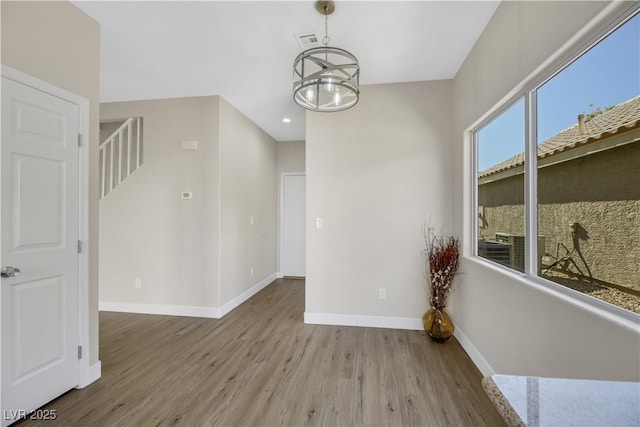 unfurnished room with an inviting chandelier and light hardwood / wood-style flooring