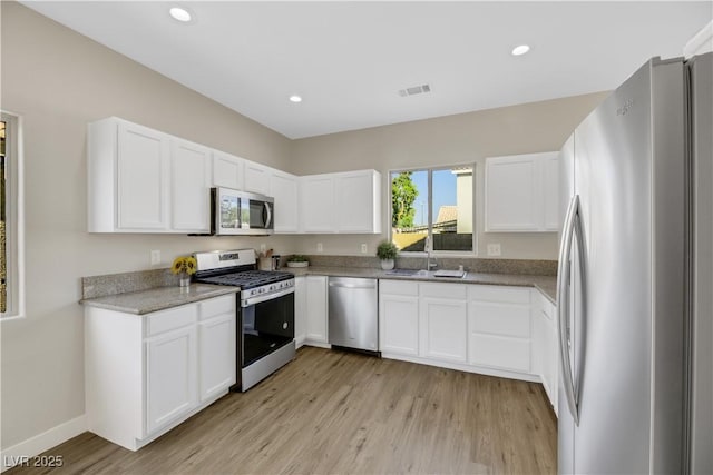 kitchen featuring white cabinets, appliances with stainless steel finishes, light hardwood / wood-style floors, and sink