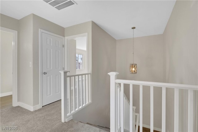 corridor with an inviting chandelier and carpet floors