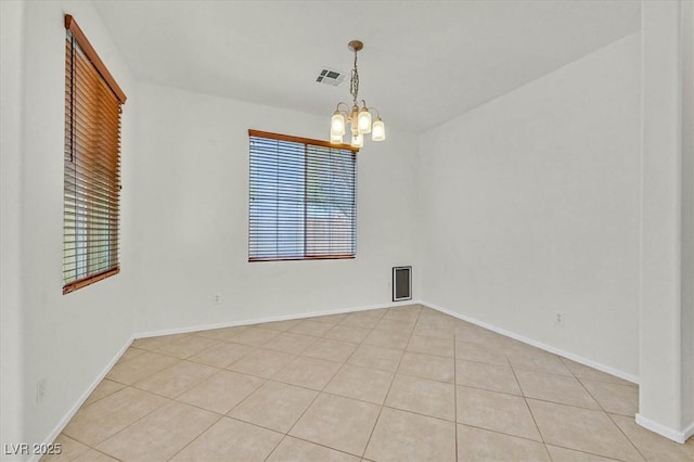 empty room featuring light tile patterned floors and a chandelier