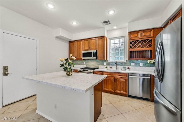 kitchen with stainless steel appliances, a kitchen island, backsplash, light tile patterned flooring, and sink