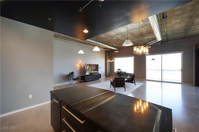 interior space featuring a notable chandelier, pendant lighting, and concrete flooring