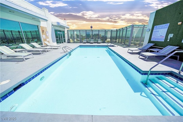 pool at dusk with a patio area