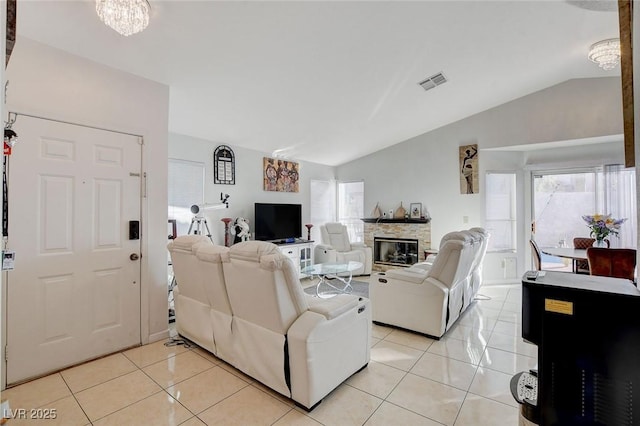 tiled living room with lofted ceiling, a notable chandelier, and a stone fireplace