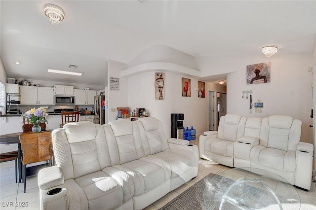 tiled living room featuring lofted ceiling and an inviting chandelier