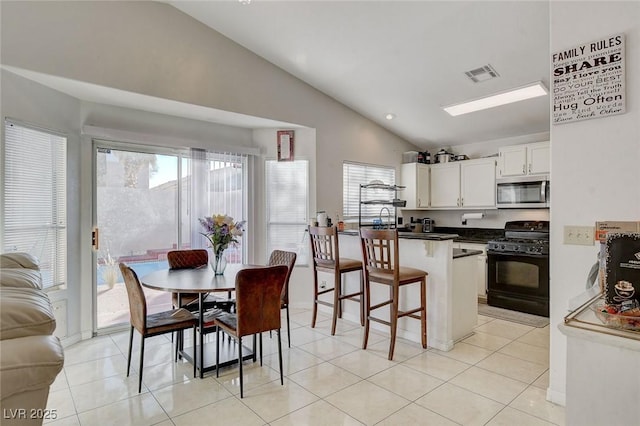 kitchen with kitchen peninsula, lofted ceiling, a breakfast bar area, white cabinets, and black range with gas stovetop