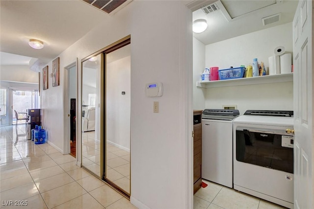 clothes washing area featuring washing machine and clothes dryer and light tile patterned floors