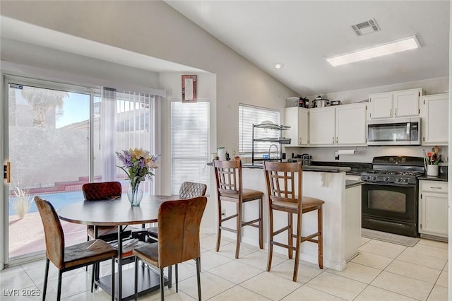 kitchen featuring white cabinetry, black gas stove, vaulted ceiling, and light tile patterned flooring