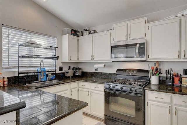 kitchen with black range with gas cooktop, dark stone counters, white cabinets, lofted ceiling, and sink