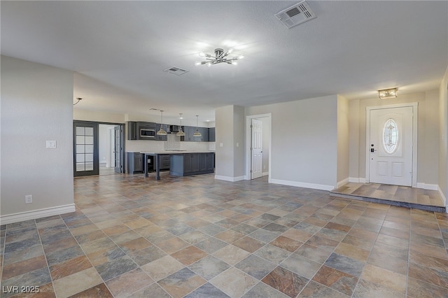 unfurnished living room featuring french doors and an inviting chandelier