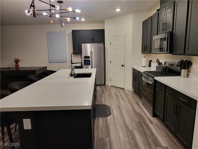 kitchen featuring stainless steel appliances, a center island with sink, a breakfast bar, and decorative light fixtures