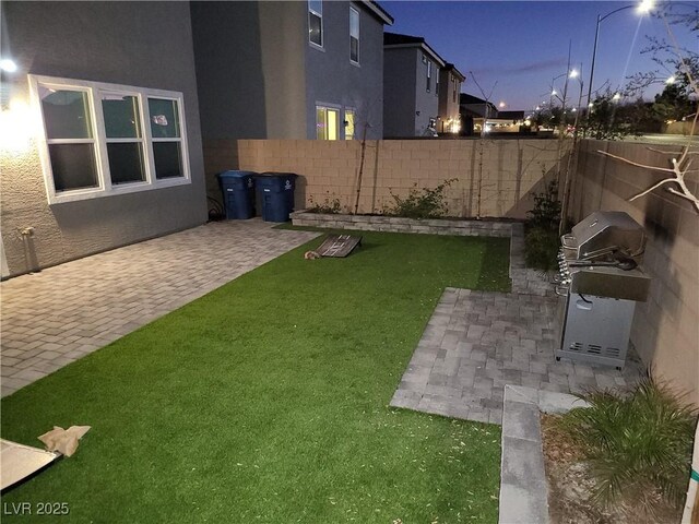 yard at dusk featuring a patio