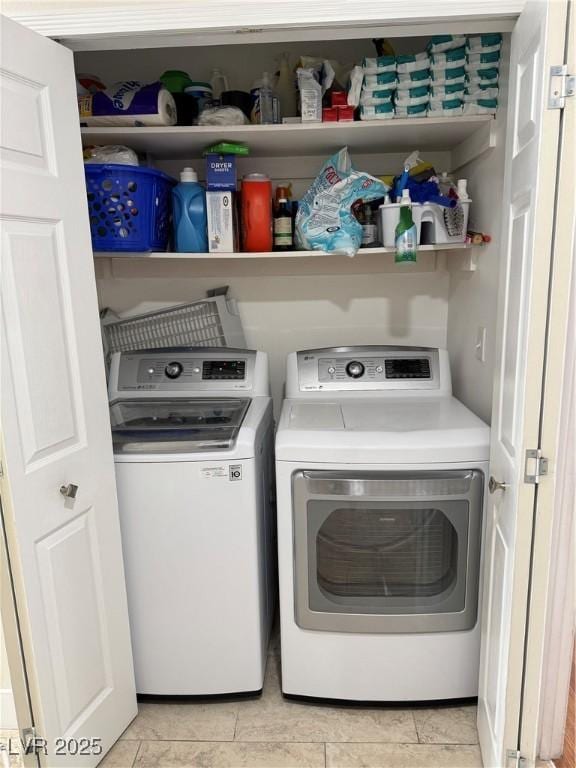 laundry area with washing machine and clothes dryer and light tile patterned floors