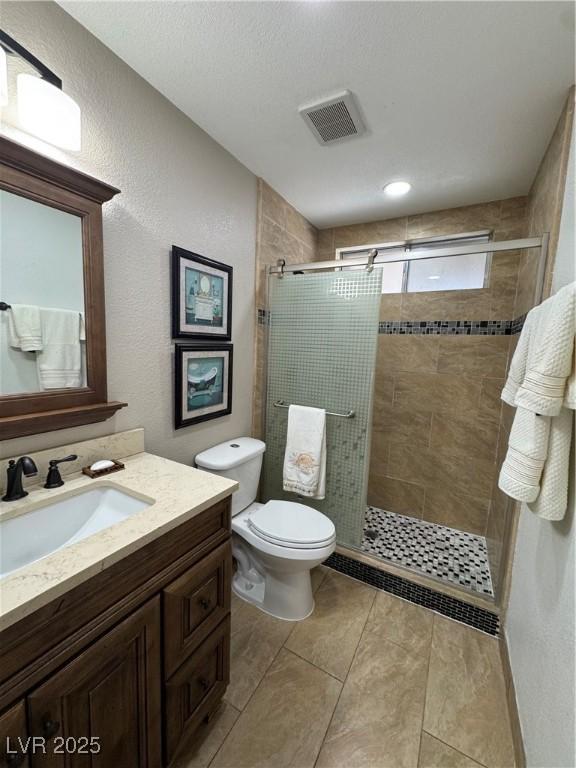 bathroom featuring toilet, a shower with door, and vanity