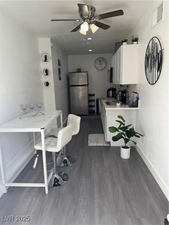 kitchen featuring sink, white cabinets, ceiling fan, stainless steel fridge, and dark wood-type flooring