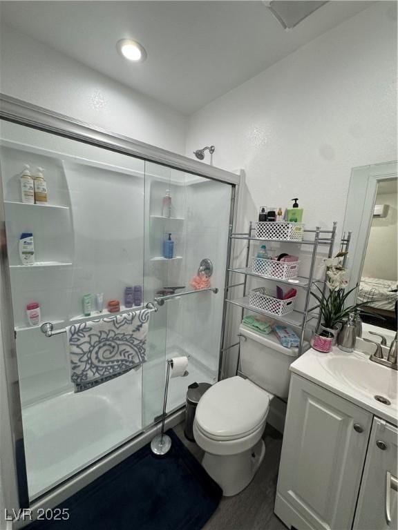 bathroom with a shower with door, hardwood / wood-style flooring, vanity, and toilet