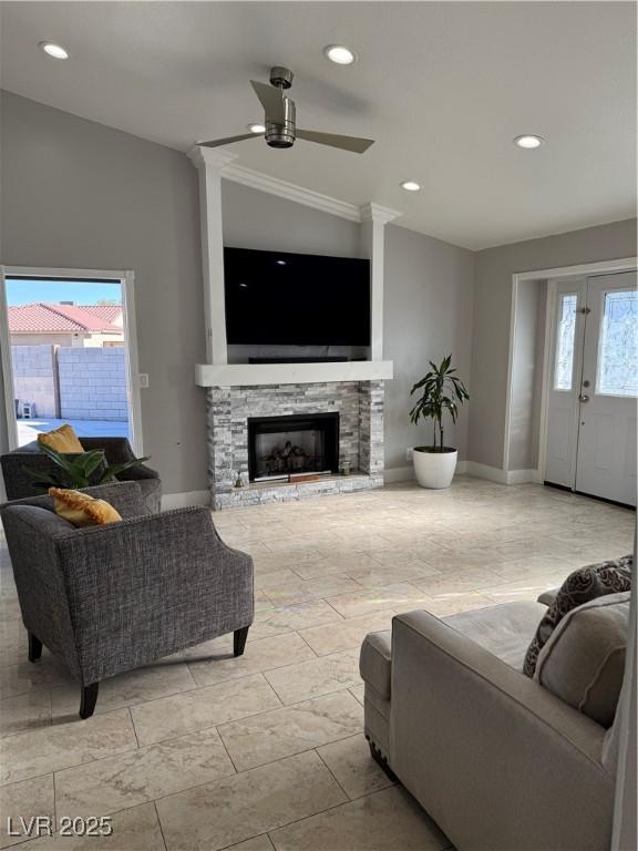 living room featuring lofted ceiling, ceiling fan, a wealth of natural light, and a stone fireplace