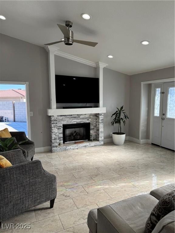 living room featuring lofted ceiling, ceiling fan, plenty of natural light, and a stone fireplace