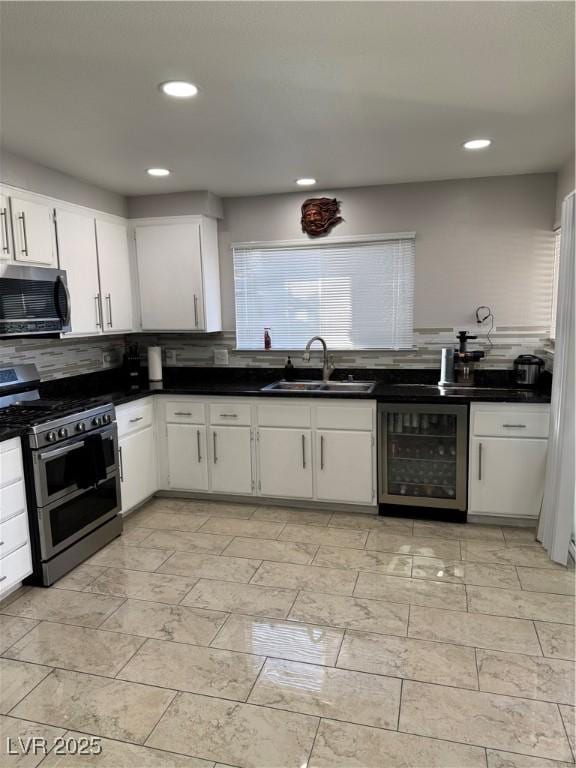 kitchen with stainless steel appliances, sink, white cabinetry, decorative backsplash, and beverage cooler