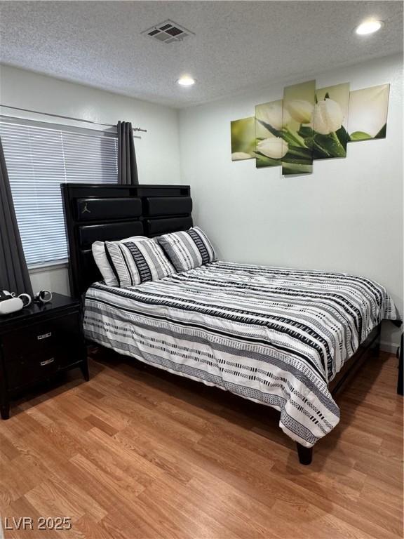 bedroom with a textured ceiling and hardwood / wood-style flooring