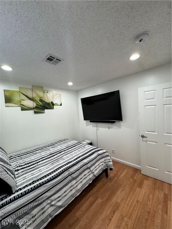 bedroom featuring wood-type flooring and a textured ceiling