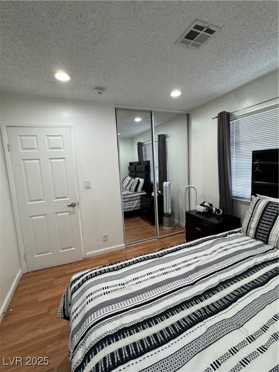 bedroom with wood-type flooring, a closet, and a textured ceiling