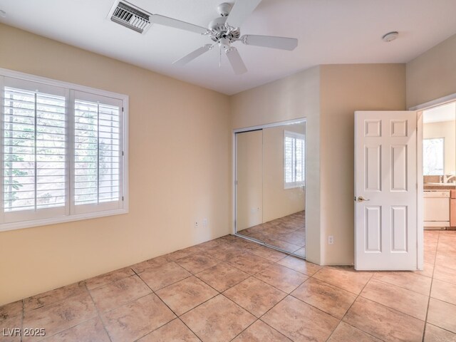 unfurnished bedroom featuring ceiling fan, light tile patterned floors, and a closet