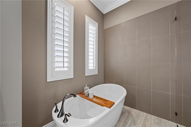 bathroom featuring a bath, ornamental molding, and a healthy amount of sunlight