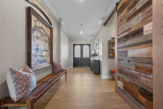 doorway featuring ornamental molding, light hardwood / wood-style floors, a barn door, and french doors