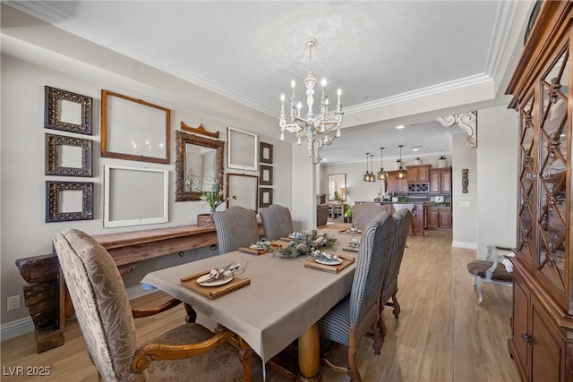 dining area with an inviting chandelier, ornamental molding, and light wood-type flooring