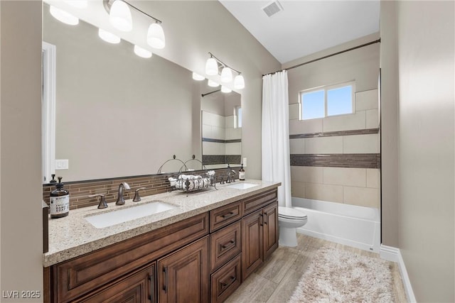 full bathroom with toilet, decorative backsplash, shower / bath combo, and vanity