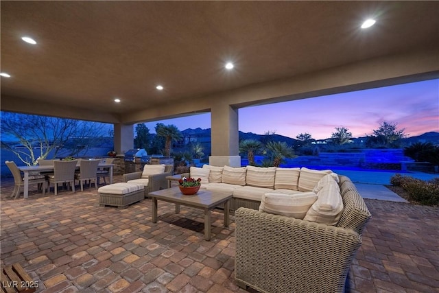 patio terrace at dusk with an outdoor living space and area for grilling