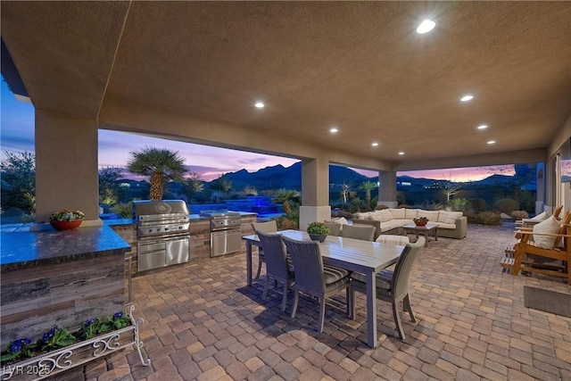 patio terrace at dusk with a mountain view, outdoor lounge area, a grill, and area for grilling