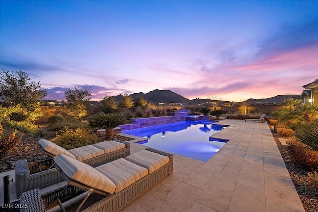 pool at dusk with a patio area and a mountain view