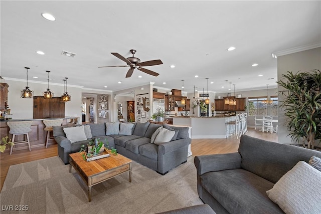 living room featuring ceiling fan, light hardwood / wood-style floors, and crown molding