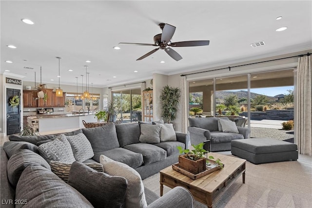 living room featuring ceiling fan, light carpet, and crown molding