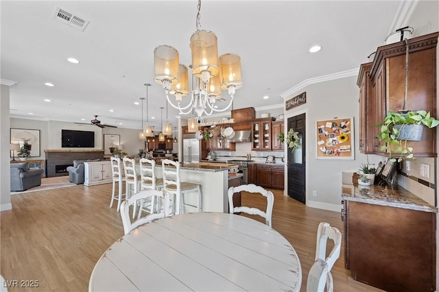 dining area with crown molding, light hardwood / wood-style floors, and ceiling fan with notable chandelier