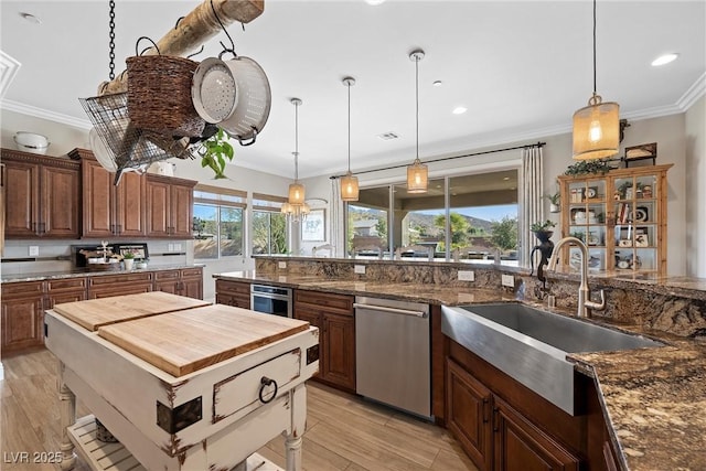 kitchen with appliances with stainless steel finishes, dark stone counters, sink, hanging light fixtures, and crown molding