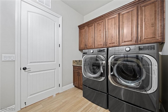 washroom with cabinets, independent washer and dryer, and light hardwood / wood-style flooring