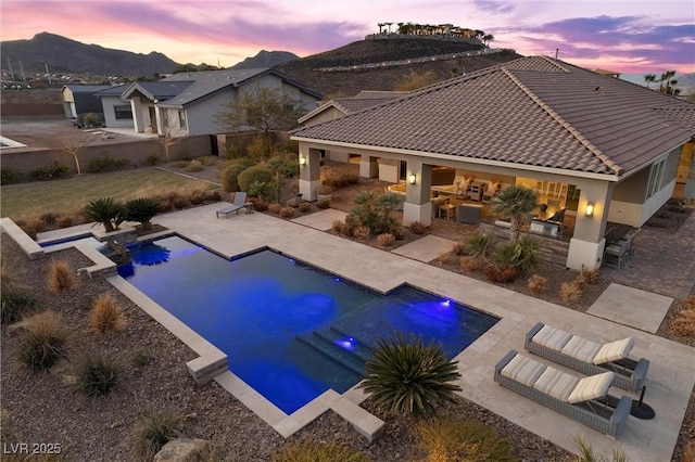 pool at dusk featuring a patio area