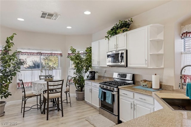 kitchen with sink, white cabinetry, light wood-type flooring, and appliances with stainless steel finishes