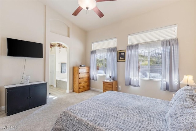 bedroom with ensuite bath, ceiling fan, and light colored carpet